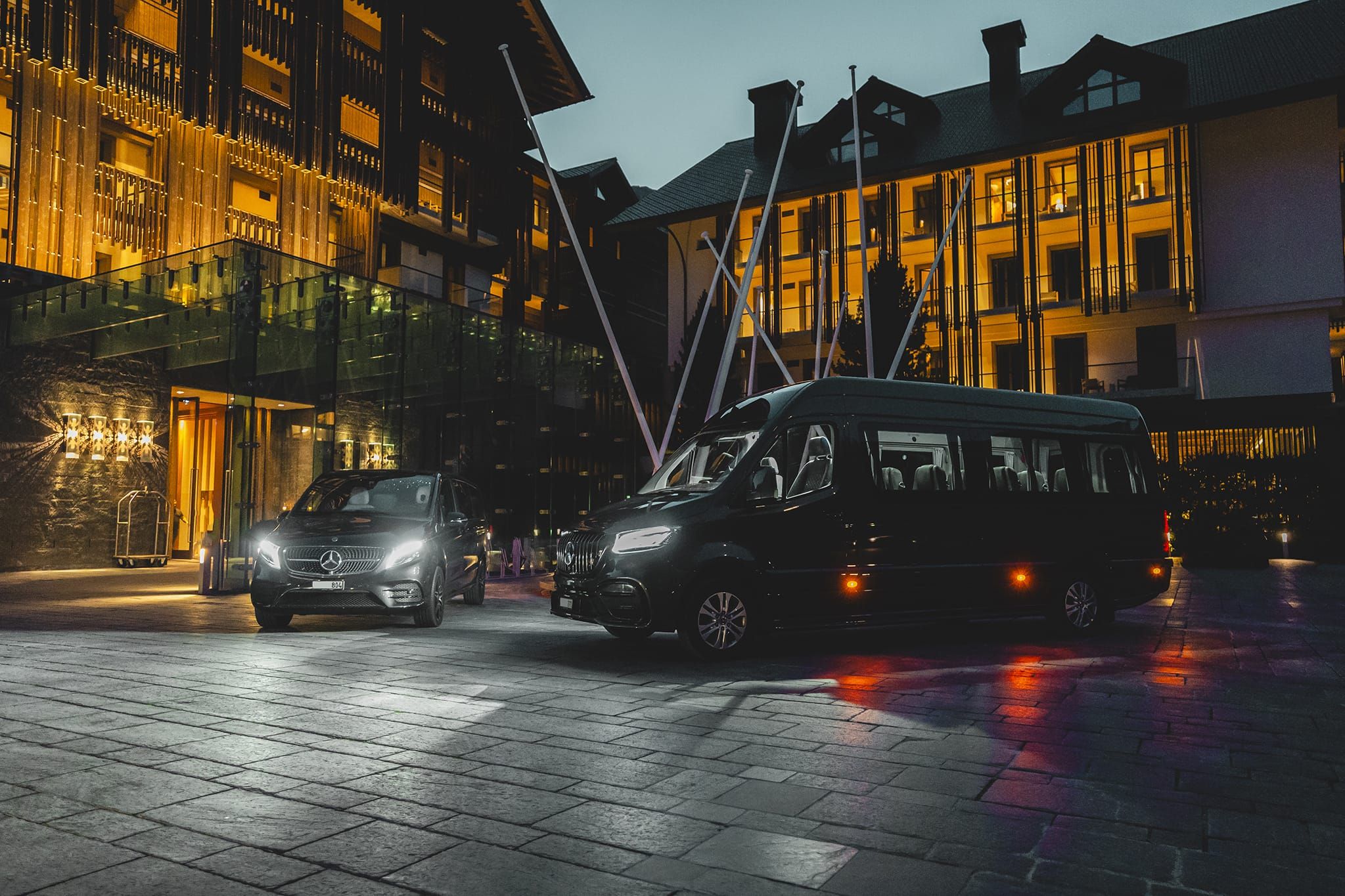 EPIC Limousines Mercedes V-Class and VIP Sprinter waiting at a luxury hotel in Andermatt at dusk